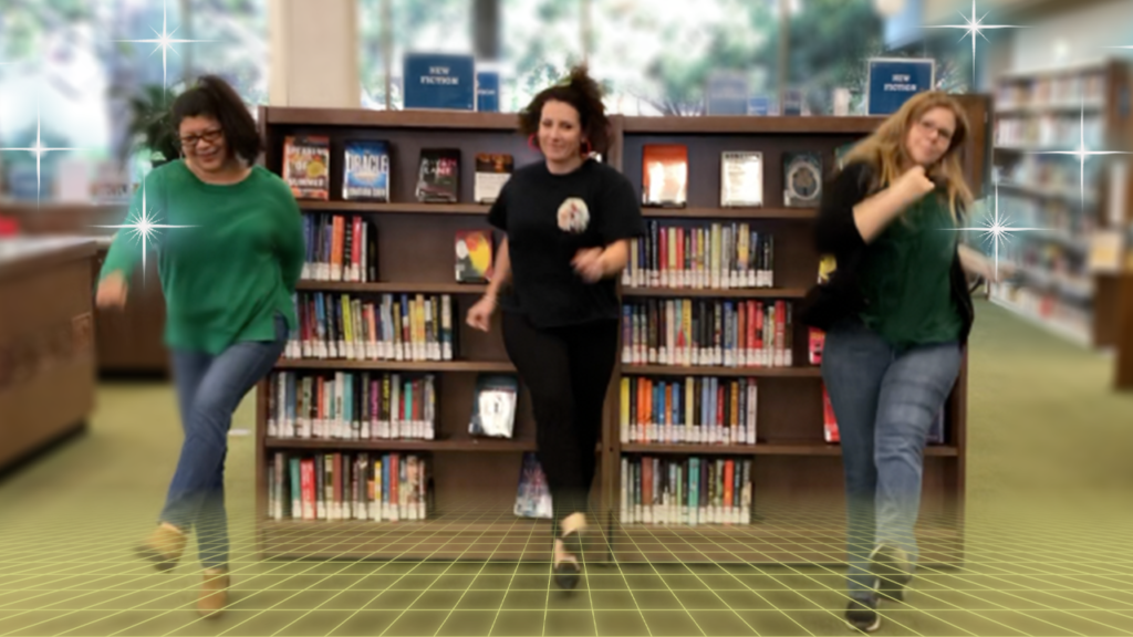 Library staff dancing in front of bookshelves