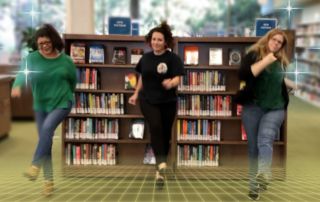 Library staff dancing in front of bookshelves